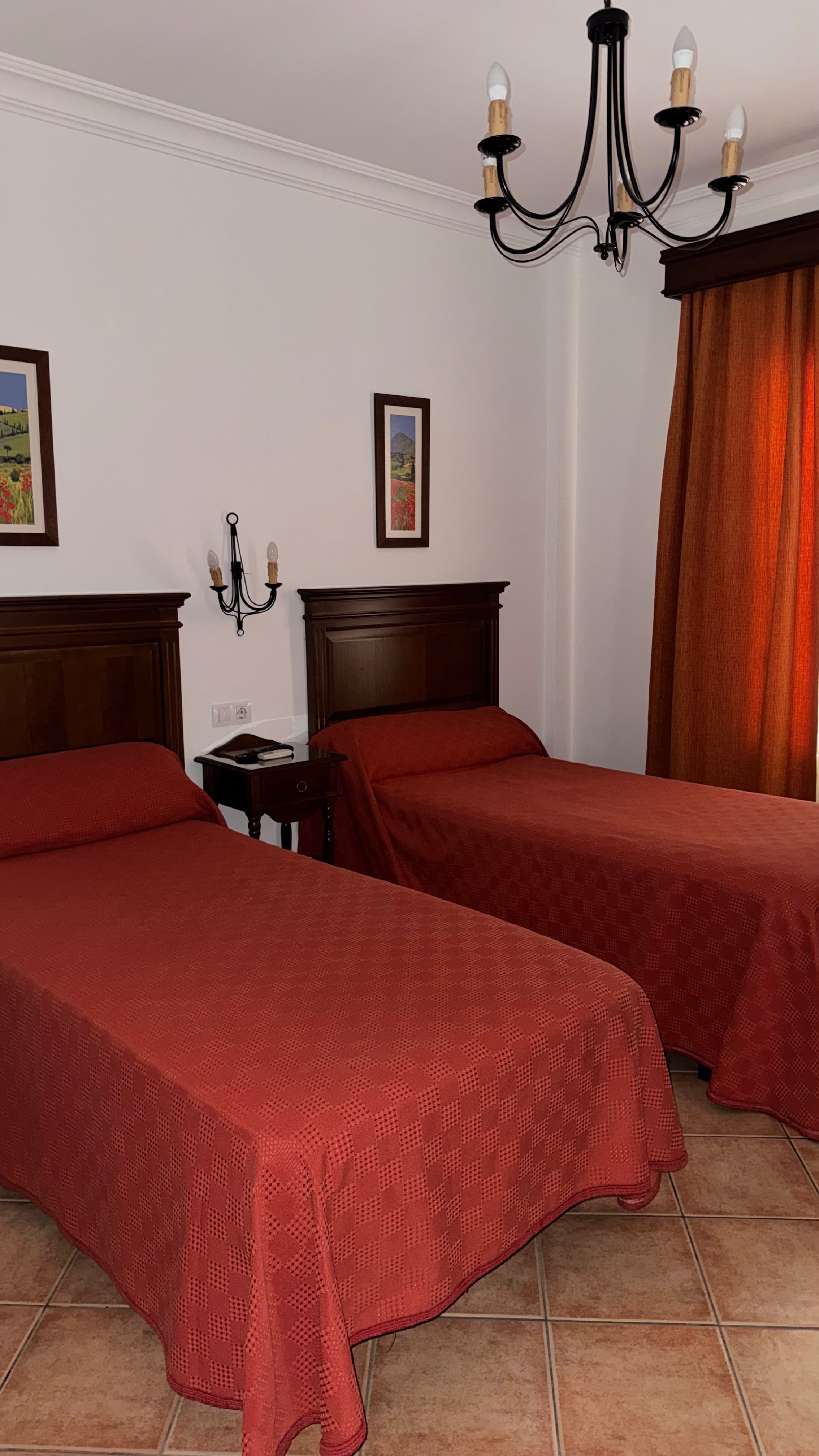 Habitación doble estilo clásico con colchas rojas en Hostal Santa Cruz